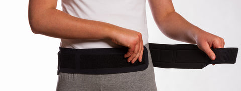 Image of Thermoskin Sacroiliac Belt black front view putting on 